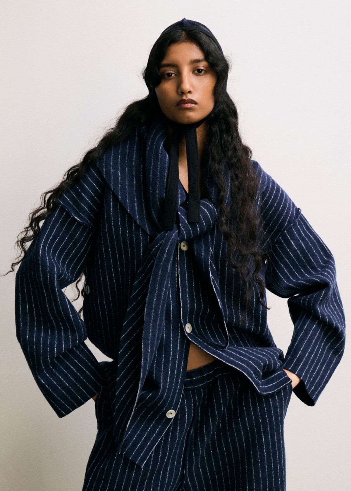 Woman wearing a blue pinstripe suit with a scarf against a white background