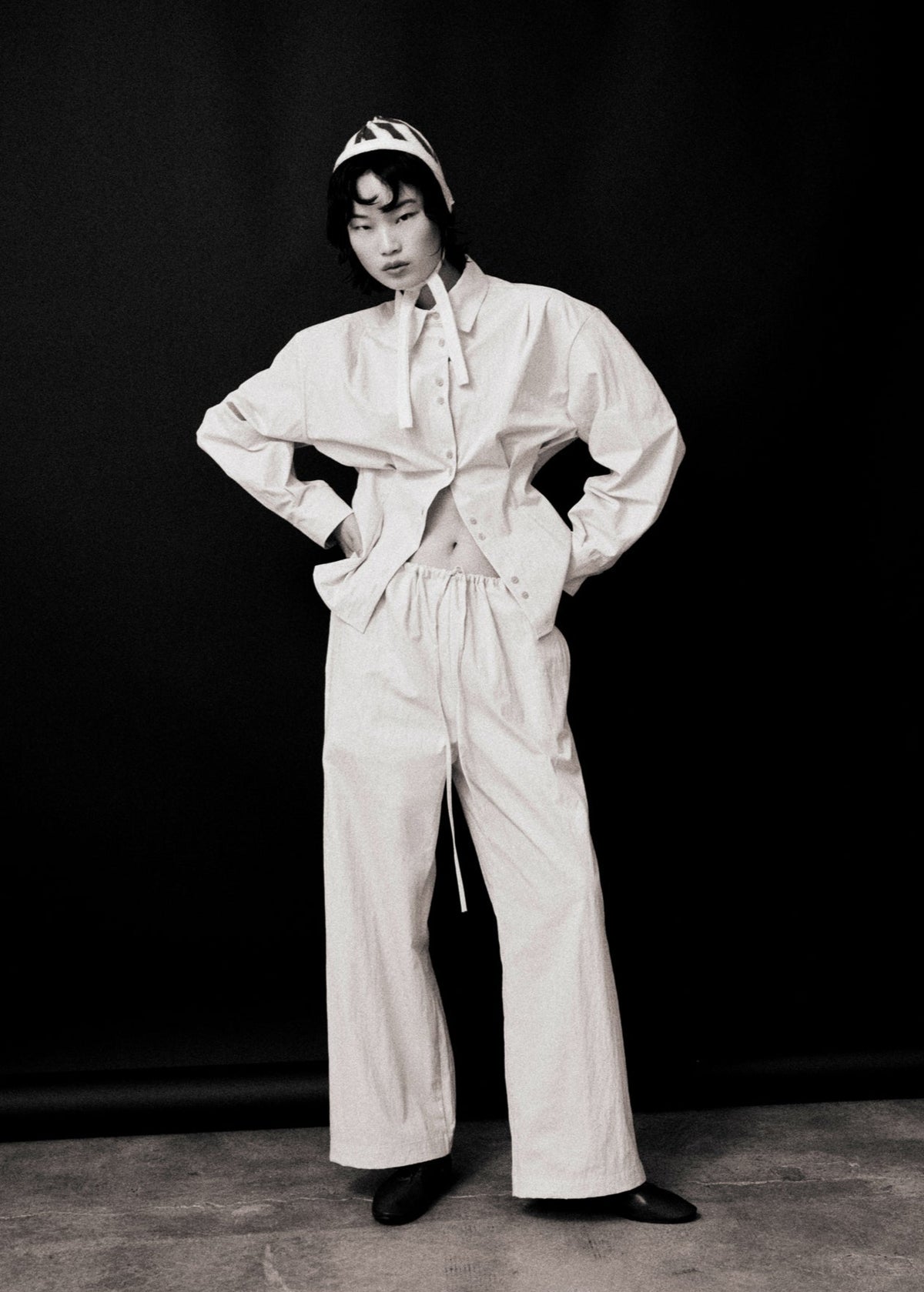 Person wearing a white outfit with a bonnet against a black background