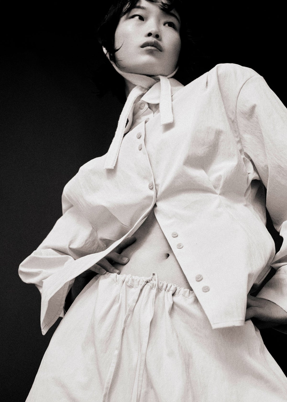Person wearing a white outfit with a shirt and pants against a black background