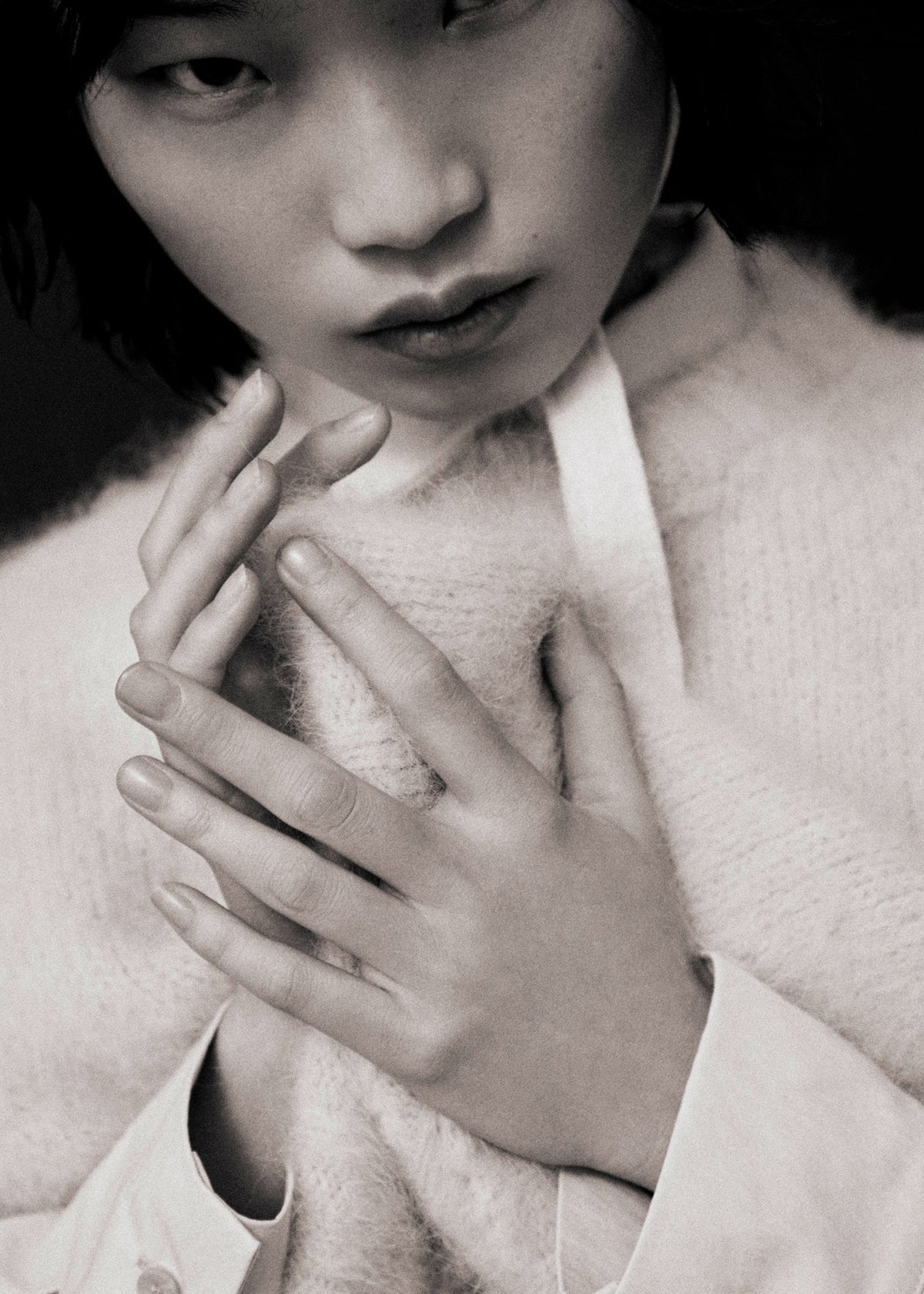 Person wearing a light-colored fuzzy knit with a close-up of their hand covering part of their chest.