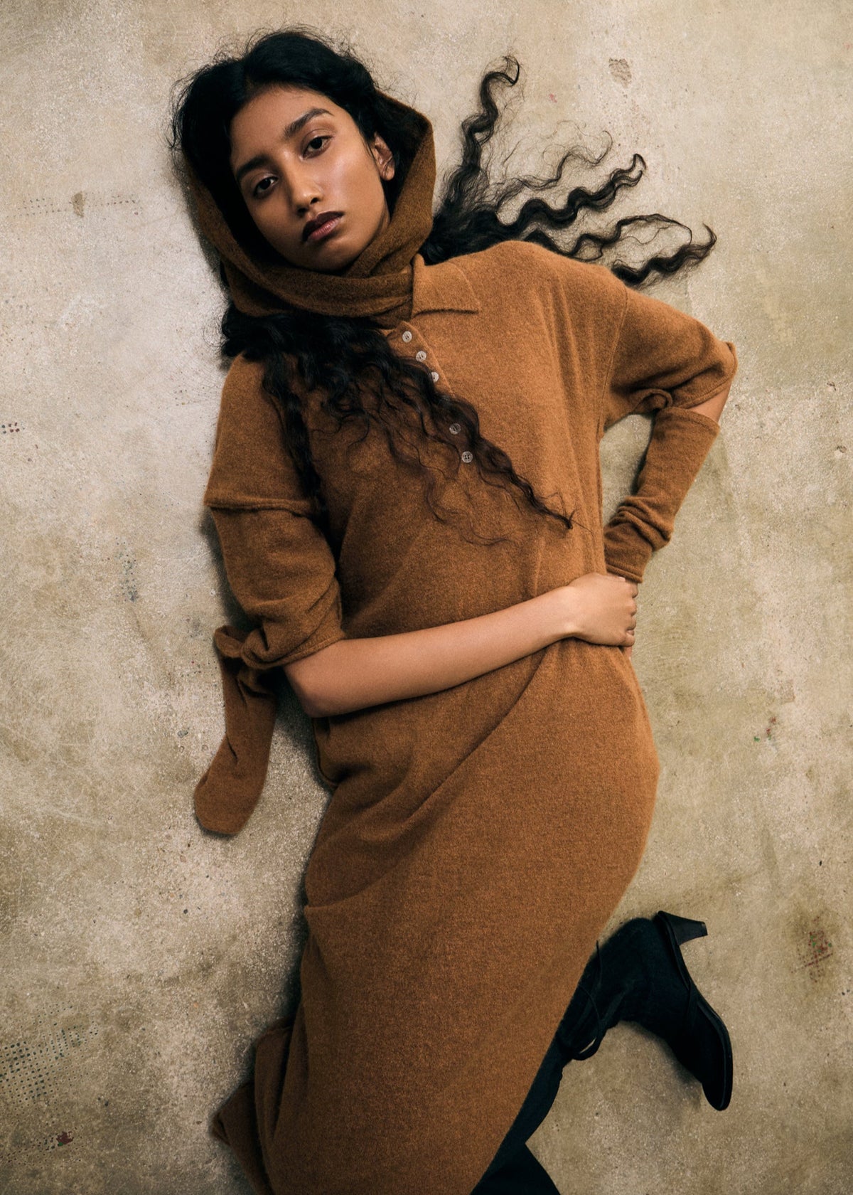 Woman in a brown dress lying on a textured surface