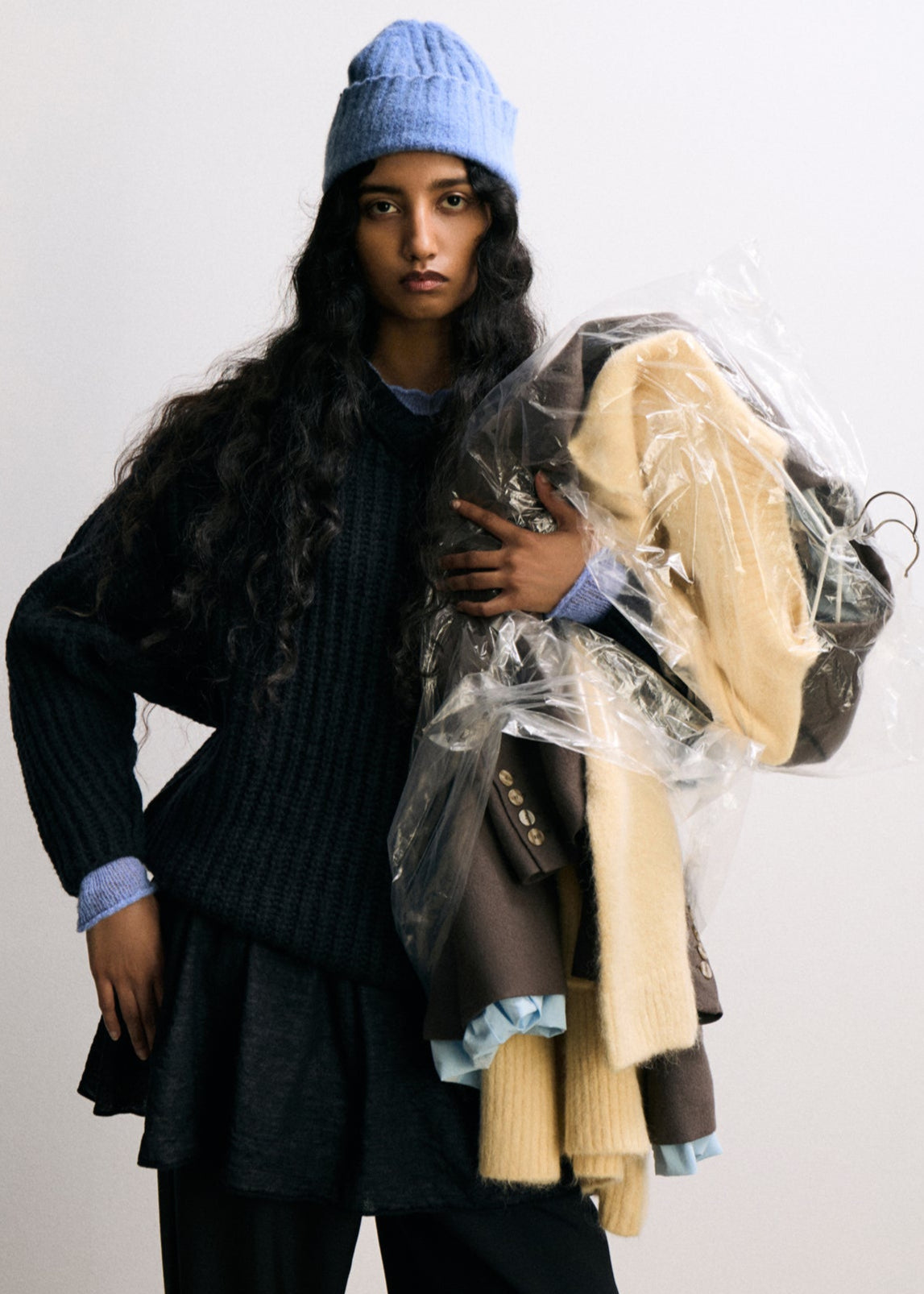 Person holding a pile of clothes against a white background