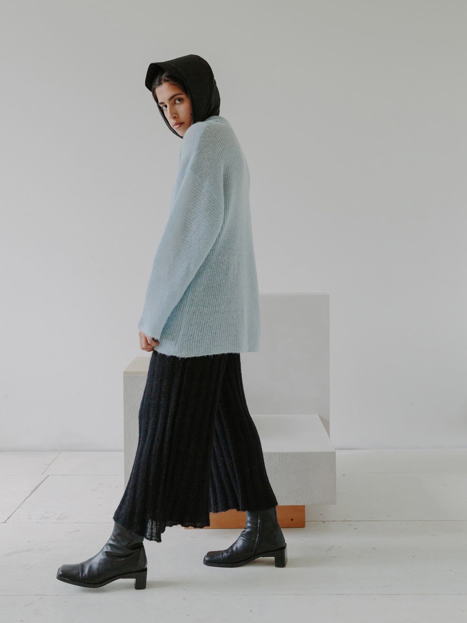 Esra wearing the FUKU polo sweater, SHOJI pants and NORI rain scarf with chair N04F002. Photographed by Marina Denisova.