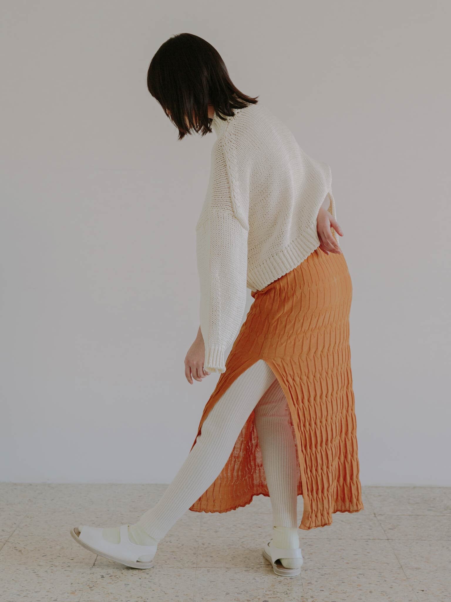 ARO skirt in Persimmon, HAKATE sweater in Eggshell, and ORAGE leggings in Eggshell.